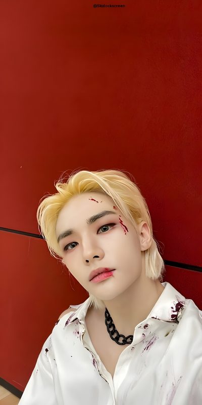 a young man with blood on his face sitting against a red wall and wearing a white shirt Hyunjin Halloween Hyunjin Joker Make Up, Hyunjin Joker Costume, Stray Kids Halloween Background, brown
