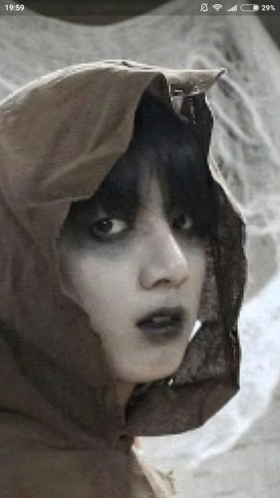 a woman with black hair and makeup wearing a brown hood over her head, looking at the camera Jungkook Halloween Historical Figures, dark olive green