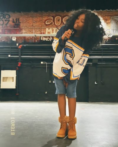 a woman standing on top of a stage holding a microphone in her hand and wearing yellow boots Sza Halloween Iconic Sza Pictures, Sza Costume For Kids, Sza Iconic Outfit, Sza 90s Outfit, dark olive green