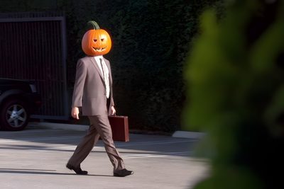 a man in a suit walks down the street with a pumpkin on his head Dwight Halloween The Office Halloween Quotes, The Office Pumpkin, Dwight Schrute Pumpkin Head, black