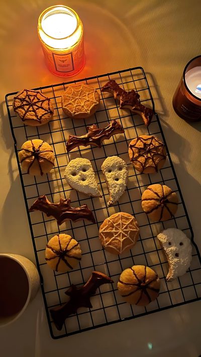 cookies are arranged on a cooling rack next to a candle Halloween Cookie Halloween Town, Halloween Aesthetic Treats, Halloween Cookies, 2000s Food, saddle brown