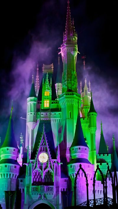 the castle is lit up with purple and green lights Magic Kingdom Halloween Wicked Castle, Walt Disney World Halloween Decorations, Purple And Green Haunted House, dark slate gray