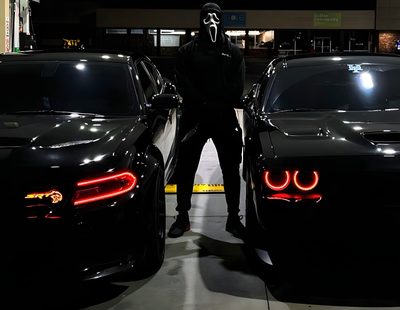 a man standing next to two black cars in a parking lot with the lights on Halloween Hellcat Hellcat Ghost, Black Ghost Hellcat, Hellcat Black Ghost, Demon Hellcat,
