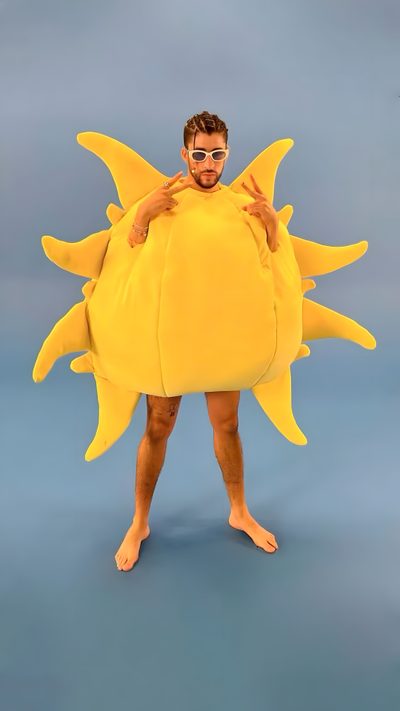 a man is dressed as a giant sun with sunglasses on his face and arms, standing in front of a blue background Bad Bunny Halloween Bad Bunny Iconic Looks, Bad Bunny 2022, Bad Bunny In Sun Costume, light slate gray