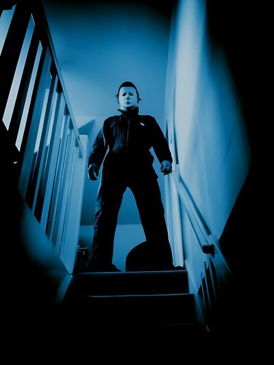 a man is standing on the stairs in front of an orange jack - o'- lantern John Carpenter Halloween Halloween Michael Myers Movies Rob Zombie, Michael Myers Horror, Mike Myers Halloween, black