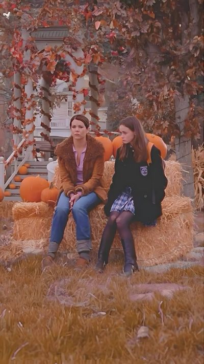 two women sitting on a hay bale with pumpkins in the background Gilmore Girls Halloween Deco Surf, Gilmore Girl, Gilmore Girls Seasons, Lauren Graham, sienna